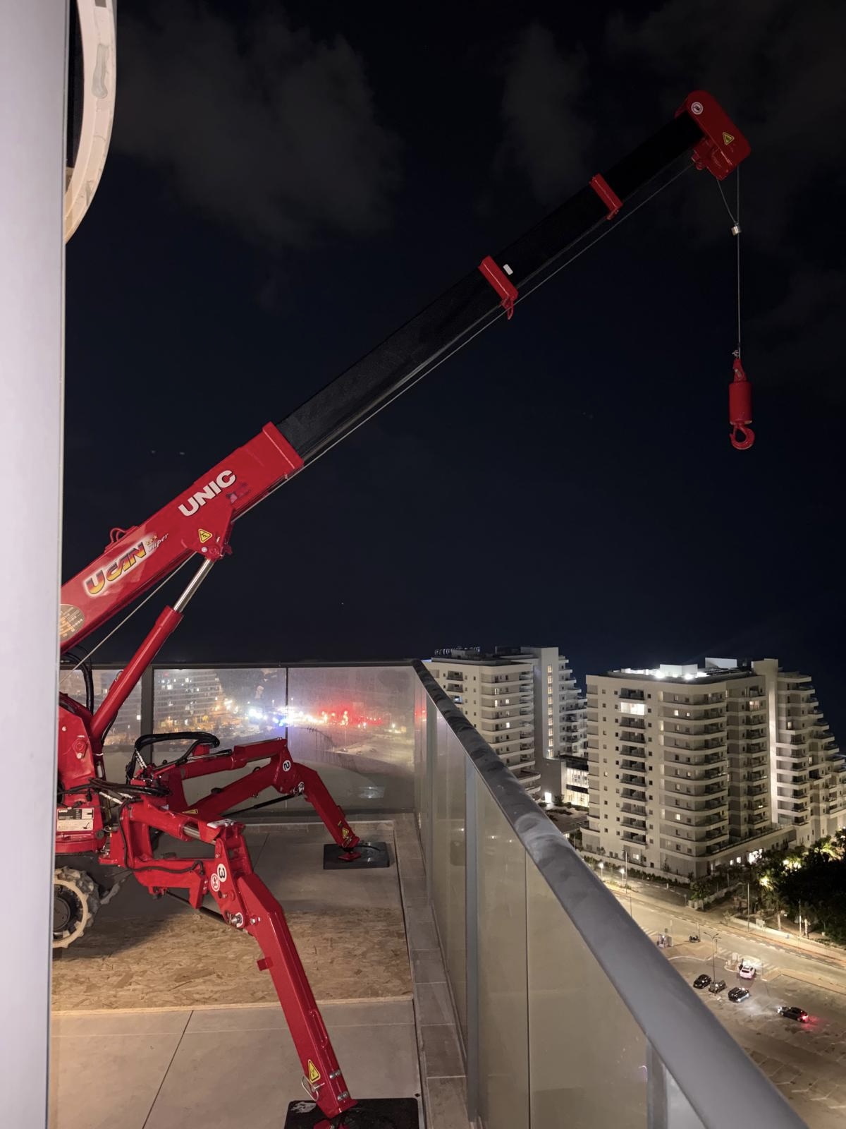מנוף ספיידר אדום על מרפסת קומה 25 במגדל, מוכן להנפת ויטרינות זכוכית